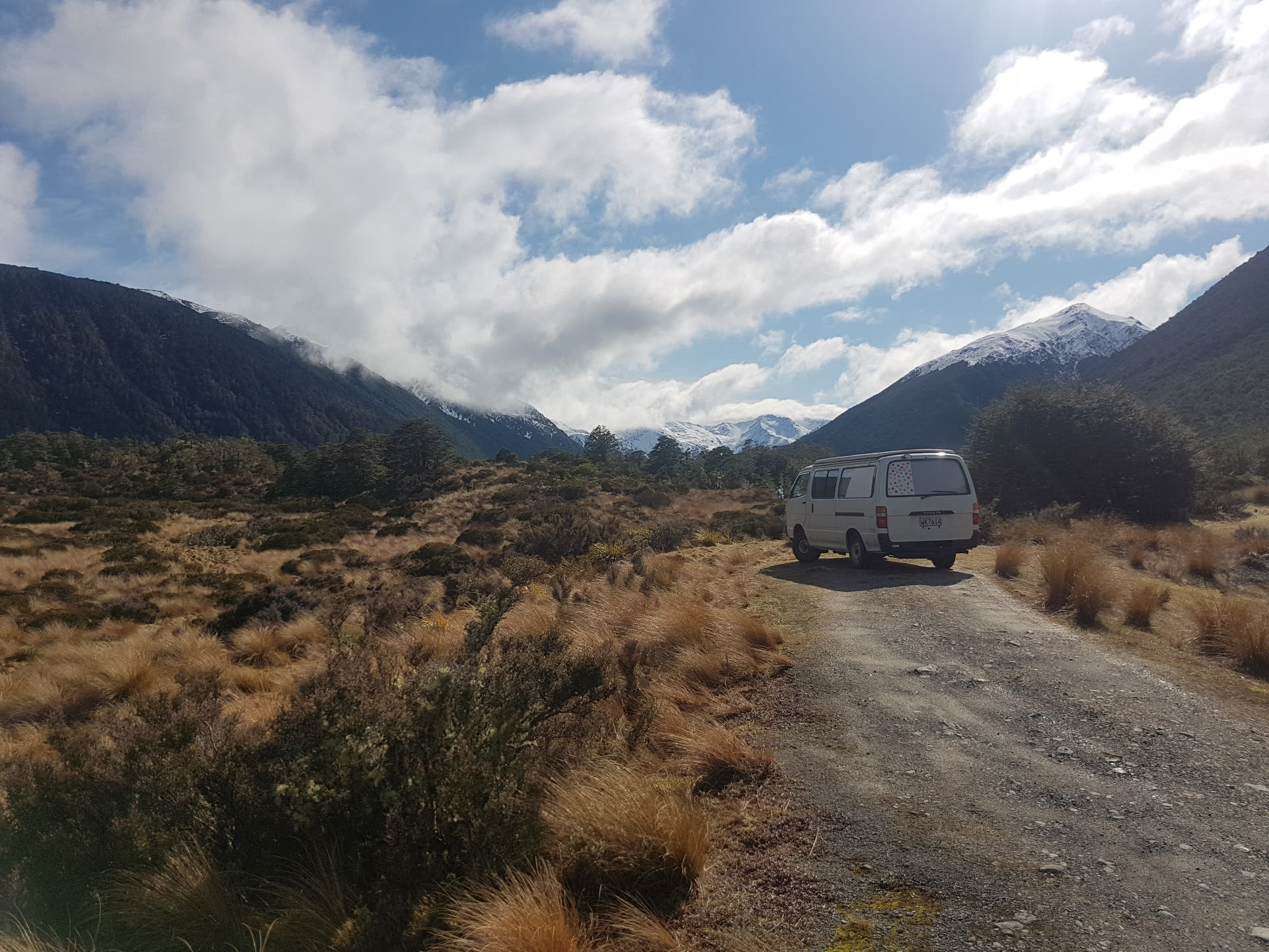 Toyota Hiace campervan parked on the St James Track, tussock and snow-capped mountains in the distance